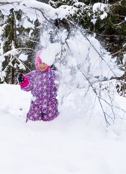 ein kind, ein mädchen 5 jahre alt kaukasier, duscht sich mit schnee. das mädchen freut sich über das spielen mit schnee. - child winter snow 4 5 years stock-fotos und bilder