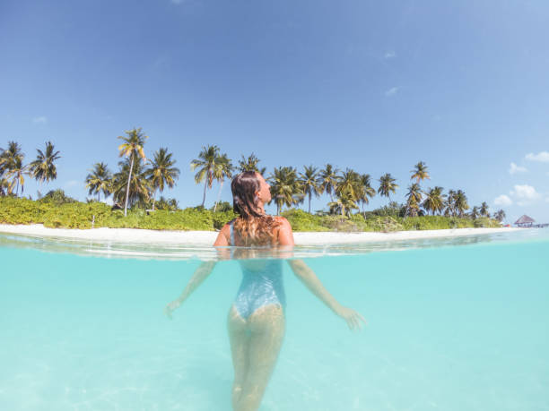 istock Woman swims in tropical sea, split screen underwater shot 1295501834