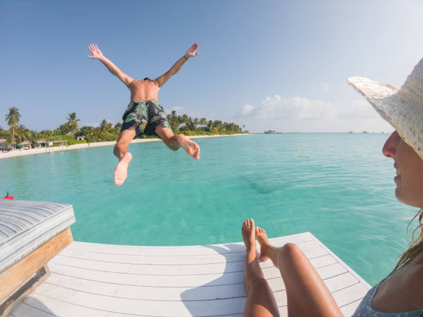 istock Couple enjoys luxury vacations, man jumps into blue lagoon 1295501914