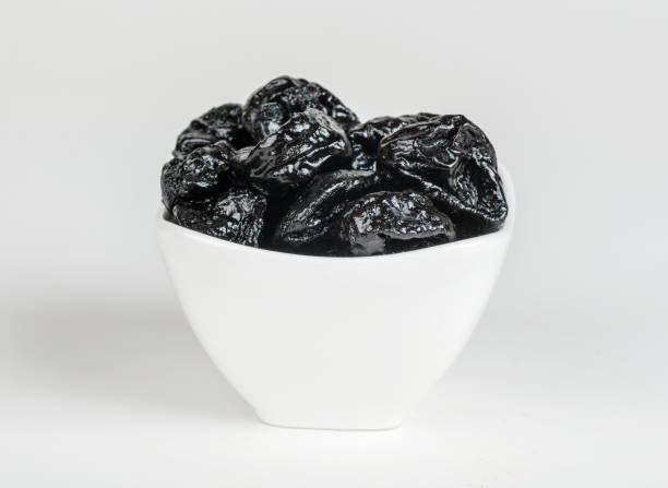 istock prunes in a white plate isolated on white background 1295502983