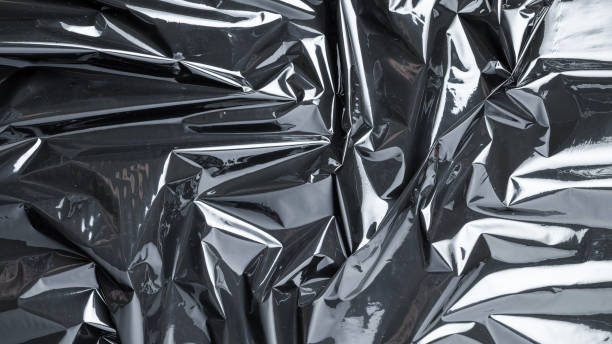 istock Smooth texture. Black shiny film bag pattern. Wrap transparent dark cellophane background. Real texture of polyethylene foil. 1295503190