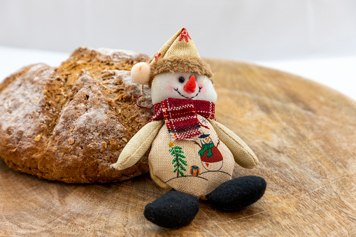 Wholemeal bread Christmas doll snowman on a brown background.