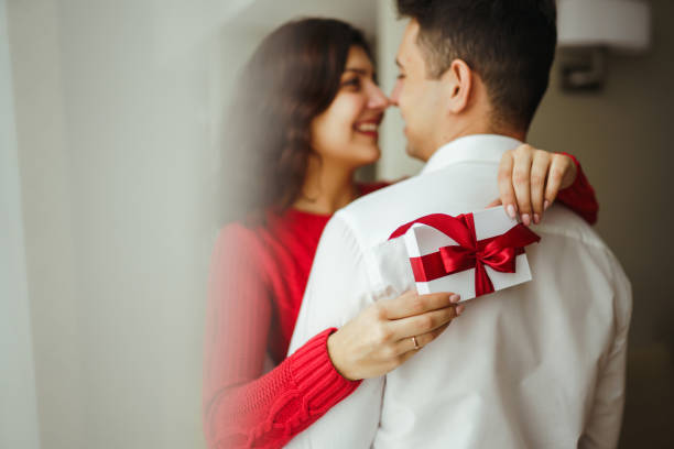 istock Happy couple with gift hugging. Valentines day celebration concept. Relationship, surprise and love concept. 1295505557