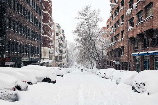 Cars covered under the snow along a commercial street in Madrid during the Filomena storm.