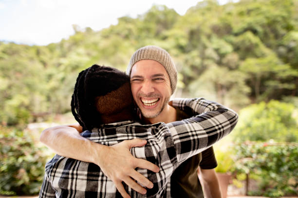 istock Young man hugging a friend outside and laughing