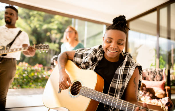 istock Smiling woman playing guitar during a band practice in a home studio 1295509565