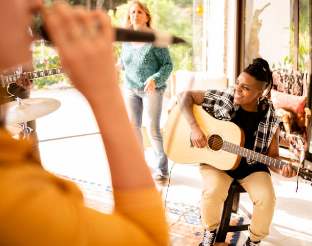 smiling guitarist jamming with her band in a home studio - jam up imagens e fotografias de stock