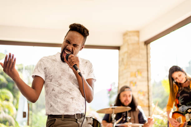 istock Young man singing during a music band rehearsal in a home studio 1295509618