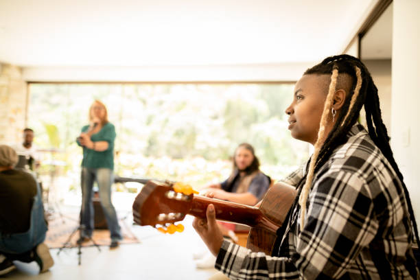 istock Young female guitarist jamming with her band in a home studio 1295509630