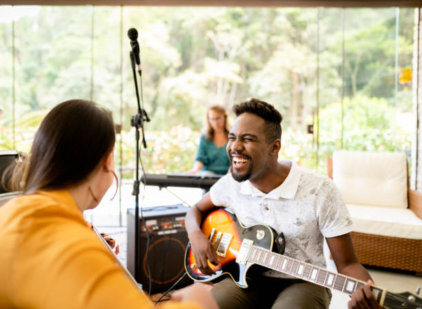 istock Laughing guitarist jamming with his band in a home studio 1295509697