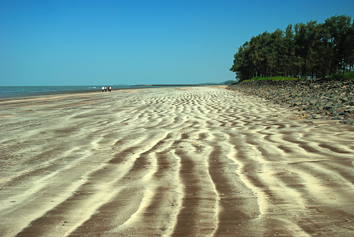 Beautiful sand pattern created by receding sea waves at virgin Versoli beach, Alibaug on the western coast of Maharashtra's Konkan coast, India.