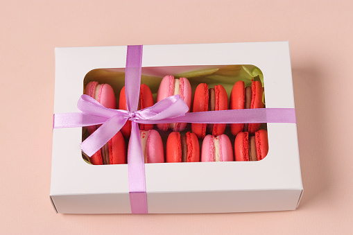 Tasty sweet cookies macaron, macaroon in a white gift box on a pink background, red and pink macarons, Closeup