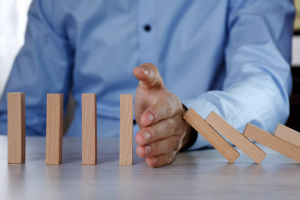 istock Businessman stop domino effect. Insurance concept and risk management 1295516525