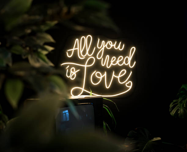 Neon sign all you need is love on a dark background