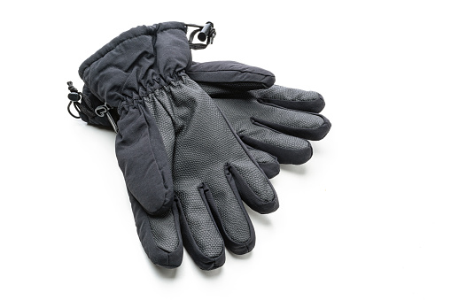 Close up view of black winter sport gloves shot on white background. The composition is at the left of an horizontal frame leaving useful copy space for text and/or logo at the right. High resolution 42Mp studio digital capture taken with SONY A7rII and Zeiss Batis 40mm F2.0 CF lens