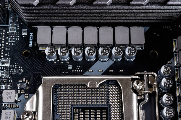 istock Inductors and capacitors for cpu socket powering on a modern black motherboard. Computer mainboard circuit components. Desktop hardware macro. PC components for assembly, upgrade and repair. 1295519612