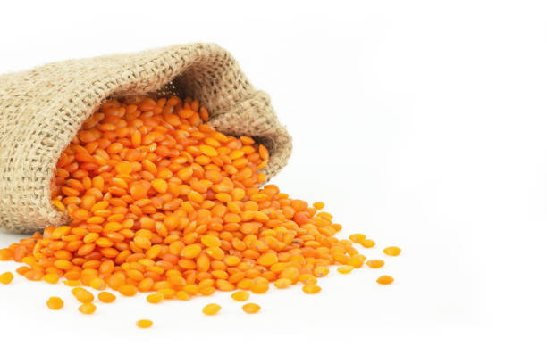 istock Uncooked raw red lentil in burlap sack isolated on white background, (Lens culinaris) 1295522422