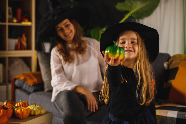 istock Little girl dressed like a witch showing camera her pumpkin 1295525323