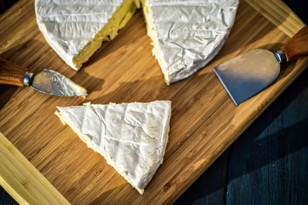 Cheese platter: Parmesan, cheddar, gouda, gorgonzola, brie and other with walnuts, olive oil and honey on wooden board on white background. Tasty appetizers with different kind of cheese. Top view.