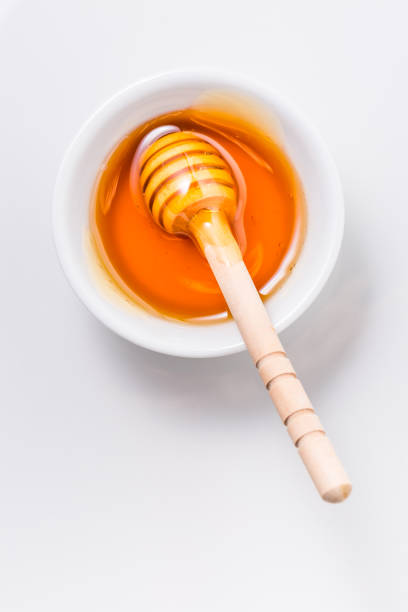 istock Honey with wooden honey dipper on white background 1295529682