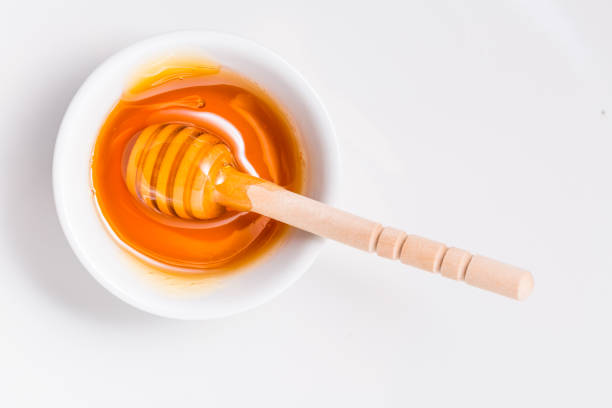istock Honey with wooden honey dipper on white background 1295529685