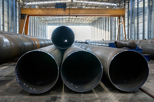 Wide angle view of the spiral welded steel pipes in the factory. The welding of the spirally welded pipes is based on the double sided submerged arc welding (DSAW) process.