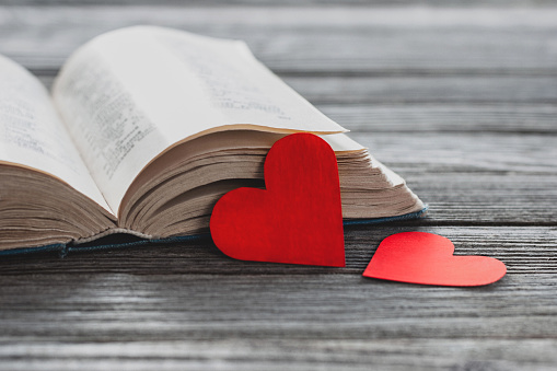 Overhead shot of blank open notebook with red heart on white background.