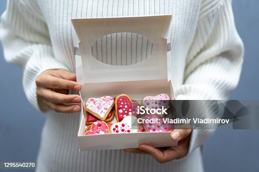 istock Woman holding box with Valentine's cookies 1295540270