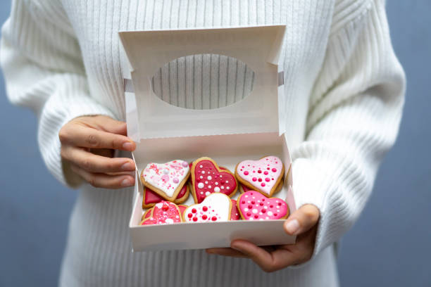 kobieta trzymająca pudełko z ciasteczkami walentynki - heart shaped cookie zdjęcia i obrazy z banku zdjęć