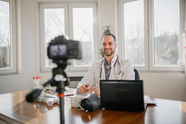 positive male doctor is making telemedicine online video call with his patient - doctor patient greeting talking imagens e fotografias de stock