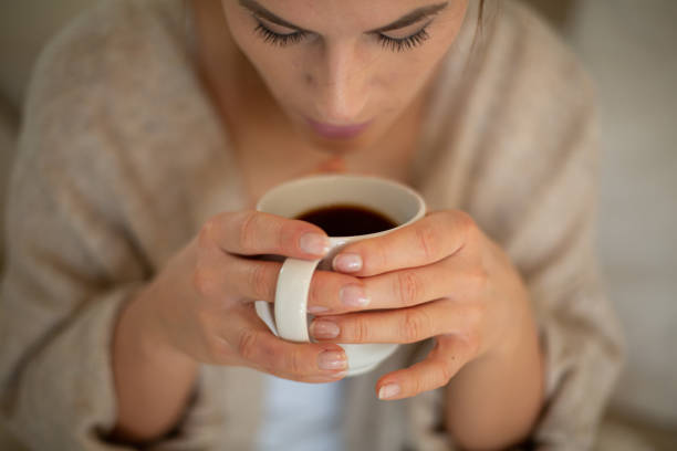 Close up Women is drinking coffee. She is enjoying her morning coffee at home.