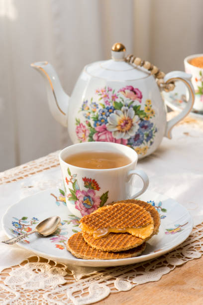 stroopwafel con ripieno di sciroppo fuso su un piatto di porcellana osso fine di lusso sul tavolo da tè pomeridiano - syrup brown sugar sugar spoon foto e immagini stock