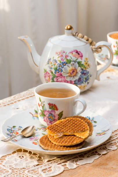 Stroopwafel with melting syrup filling on luxury fine bone china plate on afternoon tea table Stroopwafel is a traditional waffle cookie from the Netherlands. A popular way of enjoying it is to heat it up over a cup of hot drink, making the cameral filling warm and soft. gouda south holland stock pictures, royalty-free photos & images