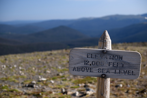 A wooden sign in Rocky Mountain National Park informs visitors they are over 12,000 feet above sea level. Located on the viewpoint trail above the visitor center near the summit of the road that crosses the park.