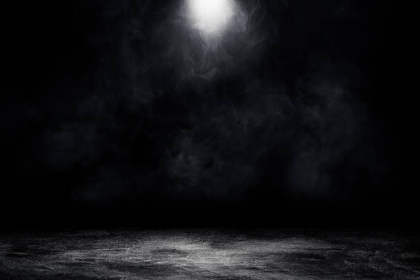 istock Studio dark room concrete floor grunge texture background with spot lighting and fog or mist in black background. 1295560359