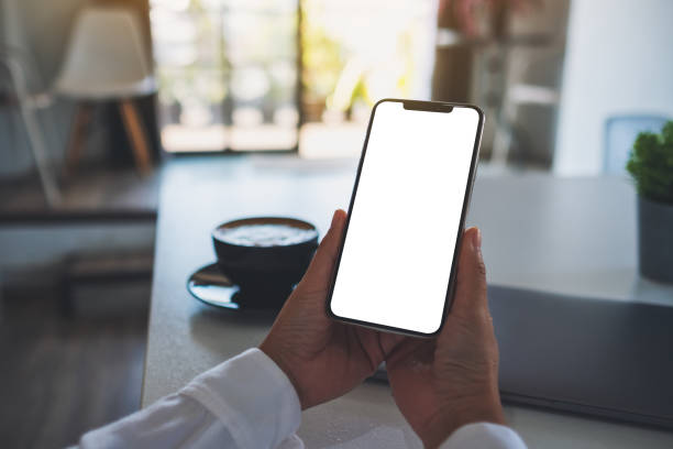 istock a woman holding mobile phone with blank white desktop screen in office 1295561983
