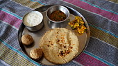 Indian Veg thali view in Restaurant style complete Food platter. Plate shot with round Chapati, sweet Laddu and white fresh Curd.