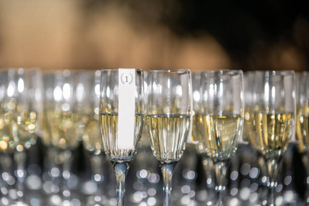 istock Row and rows of champagne glasses lined up on white table outdoors with beautiful warm bokeh background close up 1295565290