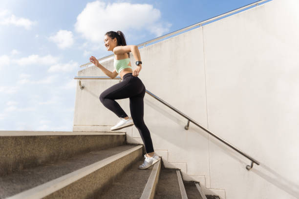 bel exercice extérieur asiatique de femme elle un vers le haut des escaliers - jumping women running vitality photos et images de collection