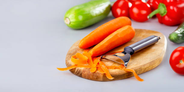 istock Vegetables banner. Vegetables cooking and eating. Peeling raw carrot and different vegetables at wooden board. 1295569860