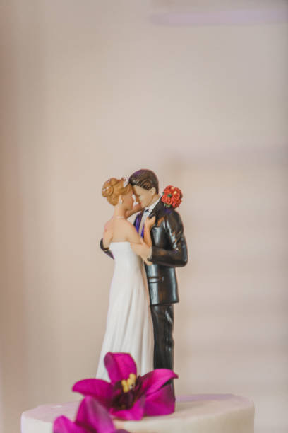 istock Romantic bride and groom dancing cake topper on white wedding cake with pink flower 1295569906