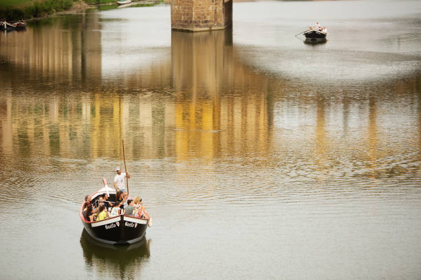Florence, Italy, June 15, 2019: Tourists enjoy a river cruise on a traditional Barchetto on the Arno river, Florence
