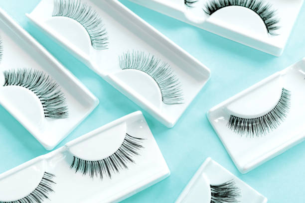 istock Different fake eyelashes on trendy pastel blue background. Beauty pattern. Makeup accessories. Cosmetic products for eye lash extensions. Closeup. 1295576763