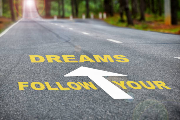istock Follow your dreams words on rural road with sunbeam 1295580490