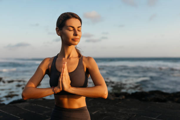 istock young beautiful woman meditation on beach. 1295581283