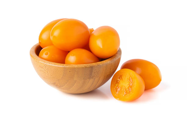 yellow tomatoes in wooden bowl stock photo