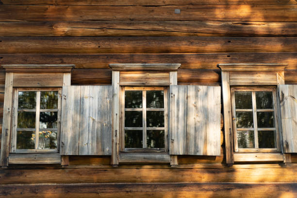 istock An old window with platbands on the background of a log wall. 1295585466