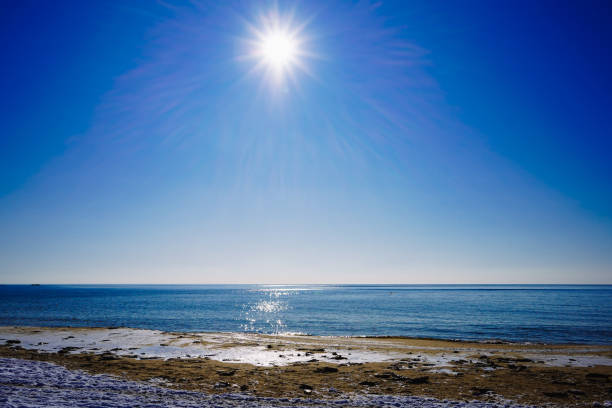 istock Seascape with bright sun and snow-covered shore 1295585657