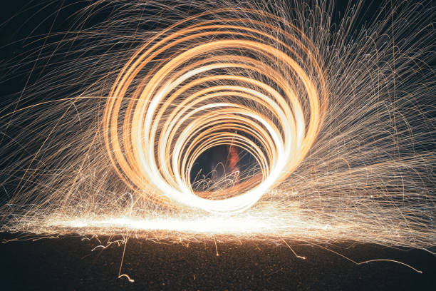istock Steel wool photography involves setting light to steel wool and then spinning it in the air to create sparks that light up the dark night sky, creating patterns of light during a long exposure. 1295586592