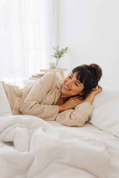 istock Smiling woman waking up from sleep lying on bed 1295586710
